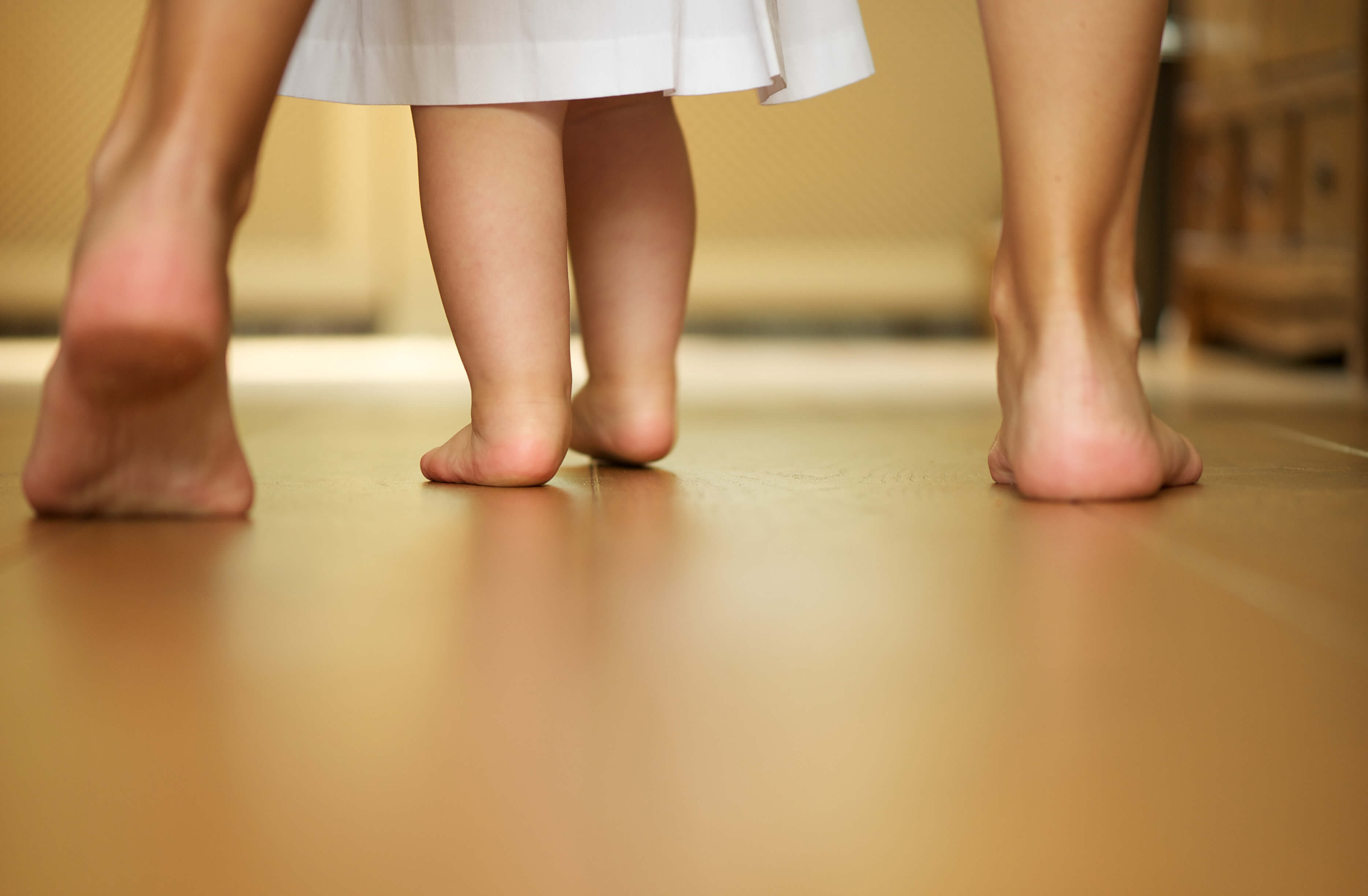 bebé aprendiendo a caminar de manos de su mamá