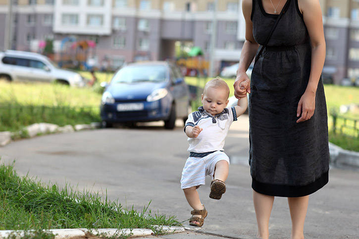 Bebe caminando de la mano de su madre teniendo cuidado en la calle