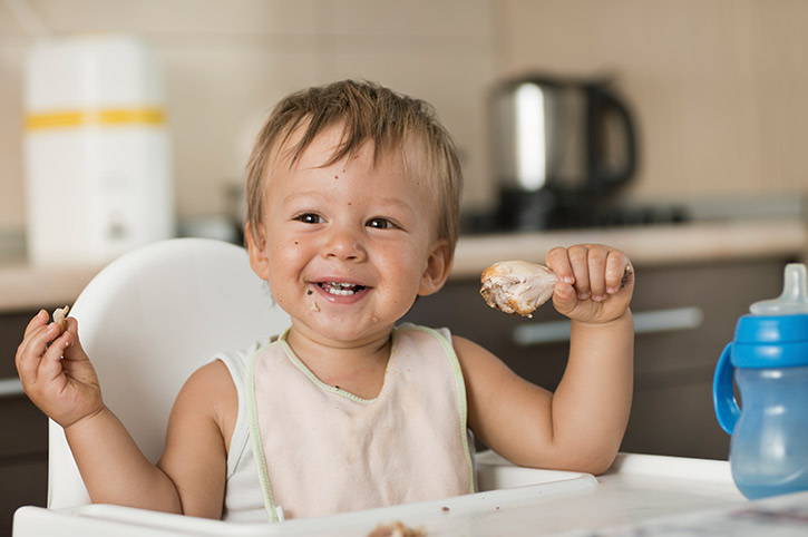 Niño feliz con pollo en la mano se alimenta con proteínas saludables