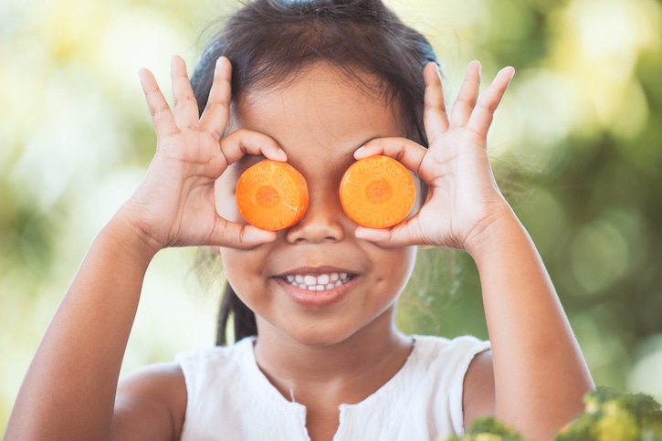 Niña con circulos de zanahoria en los ojos comiendo saludable