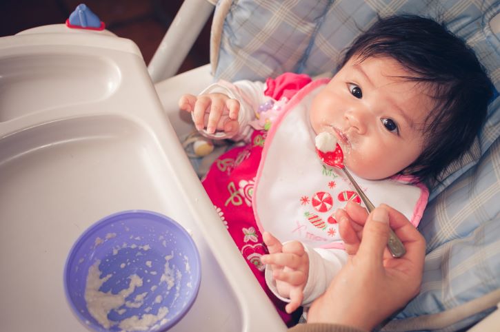 Bebe comiendo cereales infantiles iniciando la alimentación complementaria