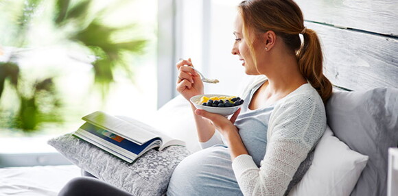 Mujer en embarazo comiendo un plato de frutas